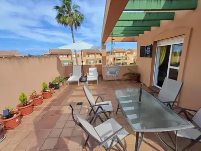a patio with a glass table and white chairs at Ático 