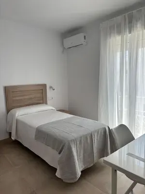 a white bedroom with a bed and a window at Alojamientos VICTORIA MAR-CHIPIONA- in Chipiona