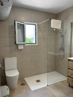 a bathroom with a shower and a toilet and a window at Alojamientos VICTORIA MAR-CHIPIONA- in Chipiona