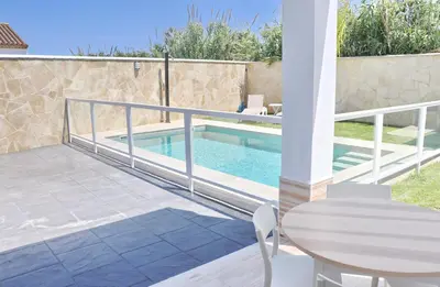 a patio with a pool and a table and a fence at El Rincon de Lidia in Conil de la Frontera
