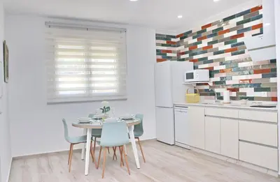 a kitchen with white cabinets and a table and chairs at El Rincon de Lidia in Conil de la Frontera