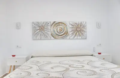 a white bedroom with a bed and two night stands at El Rincon de Lidia in Conil de la Frontera