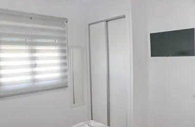 a white room with a window and a television at El Rincon de Lidia in Conil de la Frontera