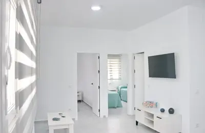 a white room with a bed and a tv at El Rincon de Samuel in Conil de la Frontera