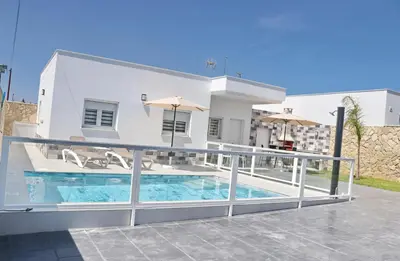 a villa with a swimming pool in front of a house at El Rincon de Samuel in Conil de la Frontera