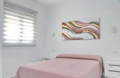 a bedroom with a bed and a painting on the wall at El Rincon de Samuel in Conil de la Frontera