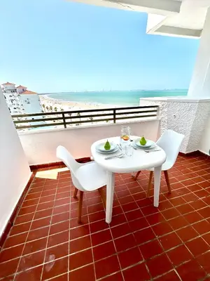 a table and chairs on a balcony with a view of the beach at GATU Malvasía- Valdelagrana in El Puerto de Santa María