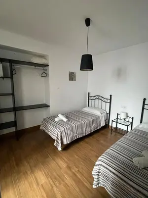 two beds in a room with wooden floors at Luz de La Caleta in Cádiz
