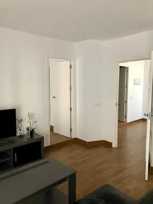 an empty living room with white walls and wooden floors at Luz de La Caleta in Cádiz