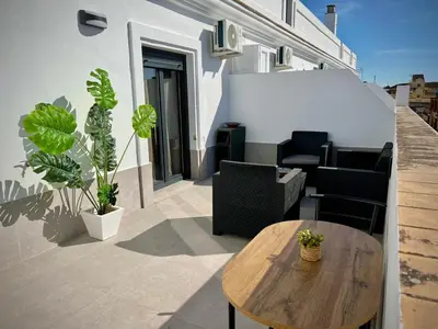 a patio with a wooden table and chairs on a building at Ático Juan Grande 17 by Sanlúcar Housing in Sanlúcar de Barrameda