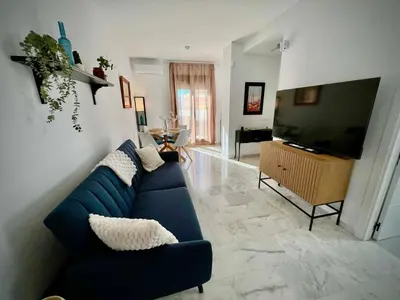 a living room with a blue couch and a television at Ático Juan Grande 17 by Sanlúcar Housing in Sanlúcar de Barrameda