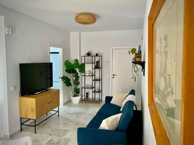 a living room with a blue couch and a tv at Ático Juan Grande 17 by Sanlúcar Housing in Sanlúcar de Barrameda