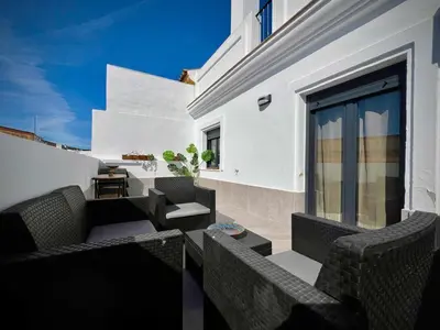 a patio with chairs and tables on a white building at Ático Juan Grande 17 by Sanlúcar Housing in Sanlúcar de Barrameda