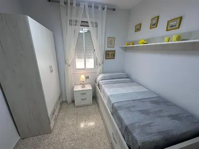 a small bedroom with two beds and a window at Chipiona playa in Chipiona