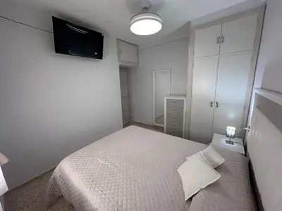 a white bedroom with a bed and a flat screen tv at Chipiona playa in Chipiona