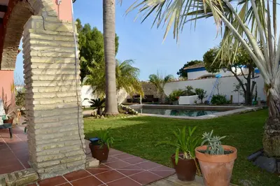 a yard with palm trees and a swimming pool at Casa Tropical in Chiclana de la Frontera