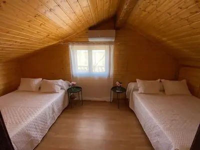 two beds in a wooden room with a window at Chalet Albariza in Sanlúcar de Barrameda