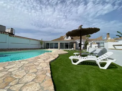 a pool with two chairs and an umbrella at Chalet Albariza in Sanlúcar de Barrameda