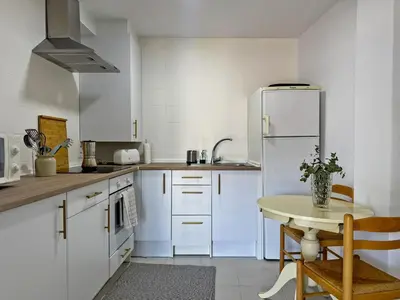 a white kitchen with a table and a refrigerator at Apartamento Sol Jerez - Ole Solutions in Jerez de la Frontera