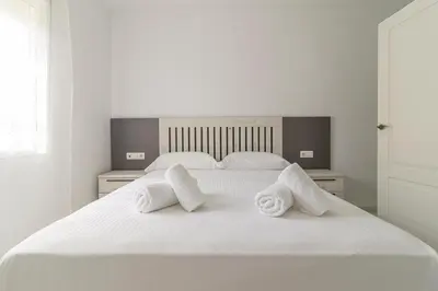 a white bed with two white towels on it at Allo Apartments Ático Jaramago Parking Centro 1 Hab in Jerez de la Frontera