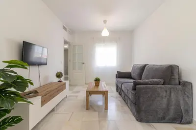 a living room with a couch and a tv at Allo Apartments Ático Jaramago Parking Centro 1 Hab in Jerez de la Frontera