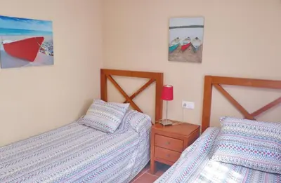 a bedroom with two beds and a table with a lamp at Urbanización Pinar de Roche 2 in Conil de la Frontera