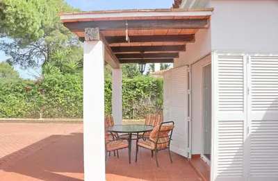 a patio with a table and chairs under a pergola at Urbanización Pinar de Roche 2 in Conil de la Frontera