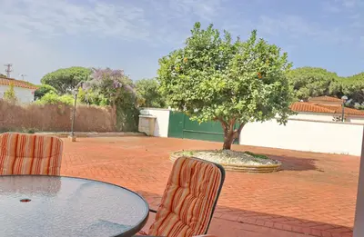a patio with a table and chairs and a tree at Urbanización Pinar de Roche 2 in Conil de la Frontera