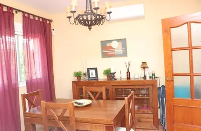 a dining room with a wooden table and a chandelier at Urbanización Pinar de Roche 2 in Conil de la Frontera