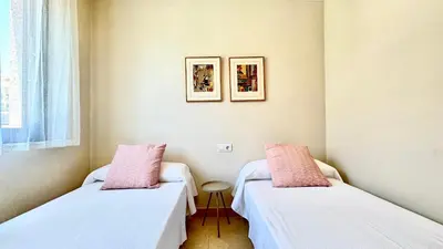 two beds in a small room with pink pillows at SIBS ELPUERTO - SANCIRO Ideal Familias Piscina Parking in El Puerto de Santa María