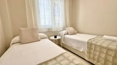 a small room with two beds and a window at SIBS ELPUERTO - SANCIRO Ideal Familias Piscina Parking in El Puerto de Santa María