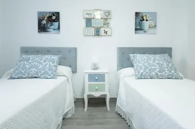two beds in a room with white walls at Royal Rent Sanlúcar Cerro Falón in Sanlúcar de Barrameda