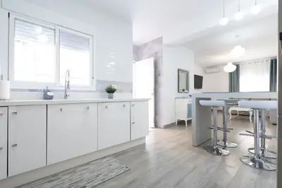 a white kitchen with white cabinets and a dining area at Royal Rent Sanlúcar Cerro Falón in Sanlúcar de Barrameda
