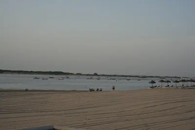 a beach with umbrellas and people on the beach at Apartamentos Sayonara Beach 1 in Sanlúcar de Barrameda