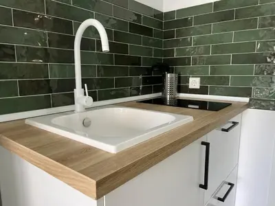 a white sink in a bathroom with green tiles at Apartamentos Sayonara Beach 1 in Sanlúcar de Barrameda