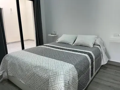 a bedroom with a bed with a gray comforter at Apartamentos Sayonara Beach 1 in Sanlúcar de Barrameda