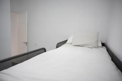a white bed with two pillows on top of it at Apartamentos Sayonara Beach 1 in Sanlúcar de Barrameda