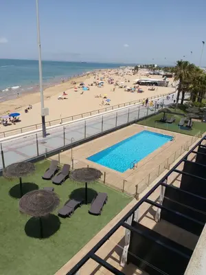 a view of a beach and a swimming pool with umbrellas at Casa deI Mar Chipiona II in Chipiona