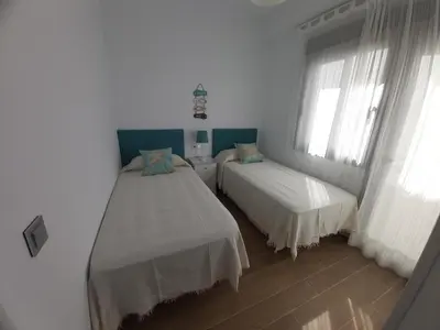 two beds in a room with white walls and windows at Casa deI Mar Chipiona II in Chipiona