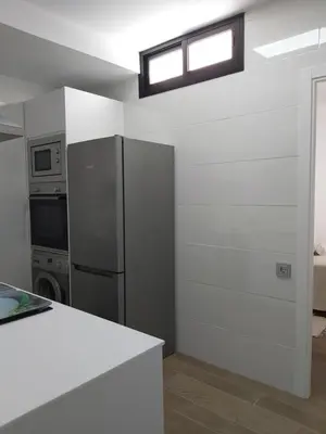 a kitchen with a stainless steel refrigerator and a window at Casa deI Mar Chipiona II in Chipiona