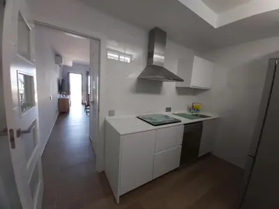 a white kitchen with a counter and a hallway at Casa deI Mar Chipiona II in Chipiona