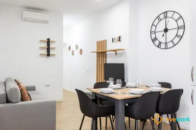 a dining room with a table and chairs and a clock at Natural House by Livework in Cádiz