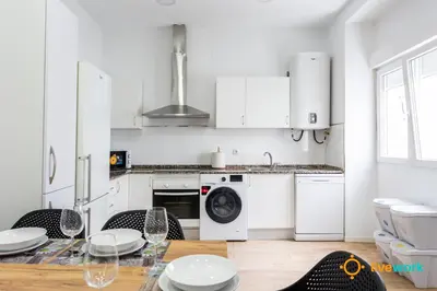 a kitchen with white cabinets and a table with chairs at Natural House by Livework in Cádiz