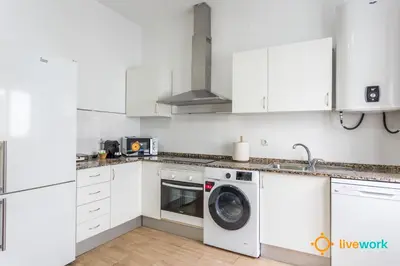 a kitchen with white cabinets and a washing machine at Natural House by Livework in Cádiz