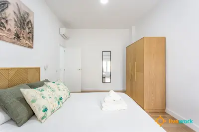 a bedroom with a white bed and a wooden cabinet at Natural House by Livework in Cádiz