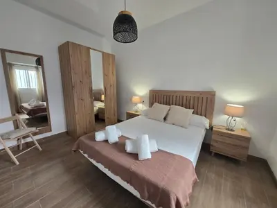 a bedroom with a bed and a chair and a mirror at Allo Apartments Campana Centro 2 Habitaciones in Jerez de la Frontera