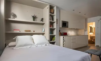 a bedroom with a large white bed and a kitchen at Apartamento Las 3 Terrazas in Cádiz