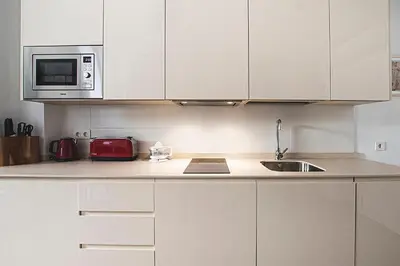 a kitchen with white cabinets and a sink and a microwave at Apartamento Las 3 Terrazas in Cádiz