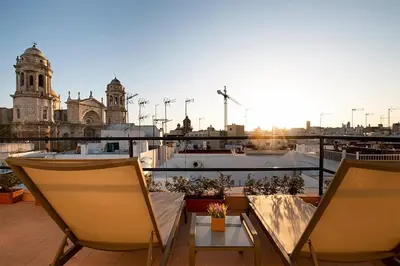 a balcony with two chairs and a table and a building at Apartamento Las 3 Terrazas in Cádiz