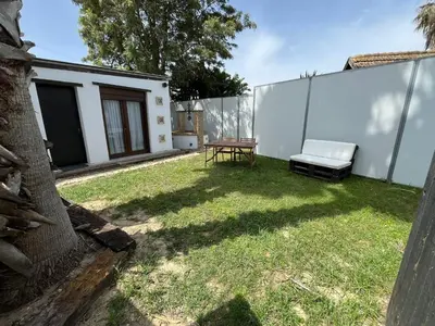 a backyard with a chair and a table and a fence at La Cabaña del Lago in Sanlúcar de Barrameda